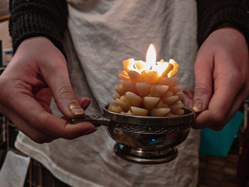 Midsection of woman holding lit candle