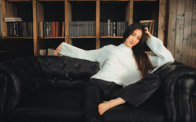 Portrait of young woman sitting on sofa at home