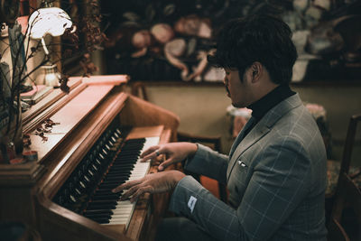 Side view of young man playing piano