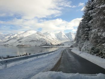 Snow covered road by snowcapped mountain against sky