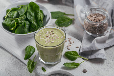 Glass of homemade healthy green smoothie with fresh baby spinach