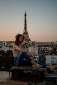 Woman in city against sky during sunset