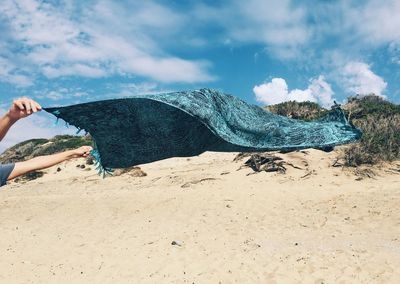 Low section of person on beach against sky