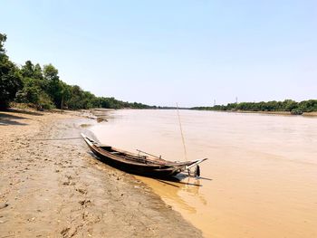 Boat moored on beach against clear sky