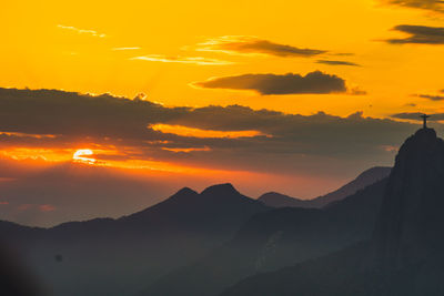 Scenic view of silhouette mountains against orange sky
