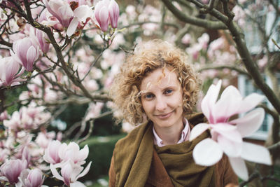 Portrait of woman with pink flowers against trees