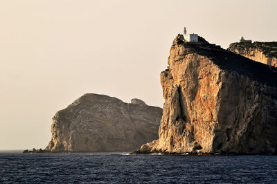 Rock formations by sea against clear sky