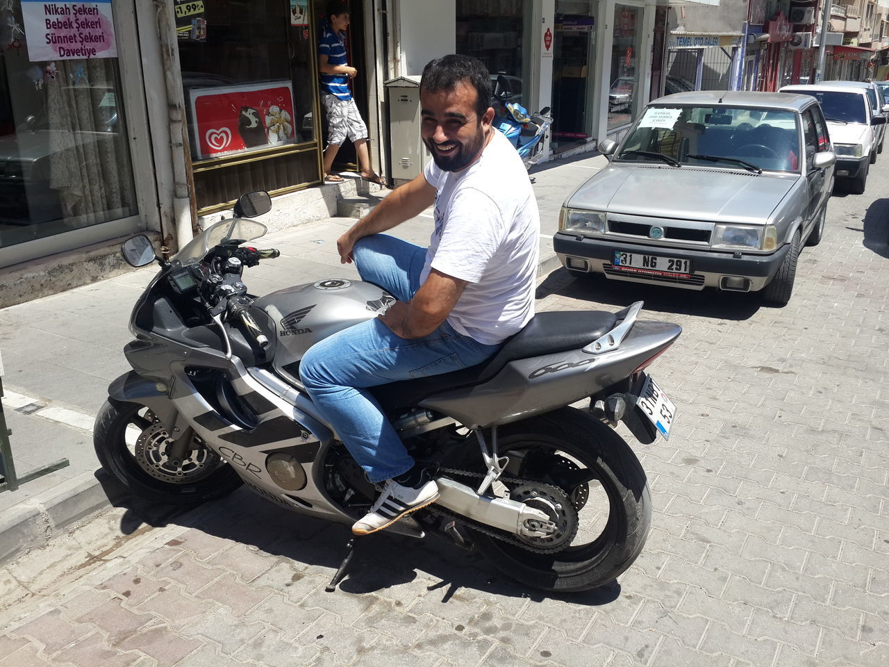 land vehicle, mode of transport, transportation, full length, lifestyles, casual clothing, person, leisure activity, street, young adult, car, front view, looking at camera, portrait, sitting, smiling, bicycle, road