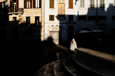 Woman walking on street amidst buildings in city