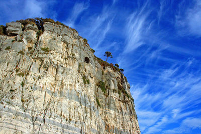 Low angle view of cliff against blue sky