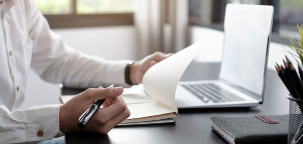 Midsection of man using laptop on table