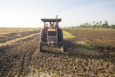 Portrait of man sitting in field against sky