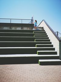 Girl on staircase against clear sky