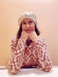 Portrait of young woman sitting against wall