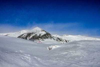 Scenic view of snowcapped mountain against blue sky