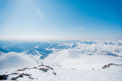 Aerial view of snowcapped mountains against blue sky