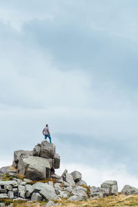 Rear view of man standing on rock against sky