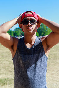 Young man wearing sunglasses while standing against sky