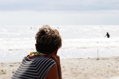 Rear view of woman sitting on beach