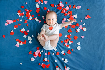 High angle portrait of boy sitting against blue wall