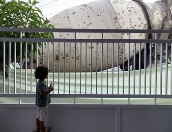 Rear view of a girl standing against railing