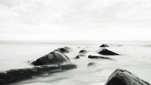 Scenic view of rocks in sea against sky