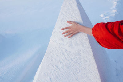 Cropped hand of woman touching snow covered retaining wall