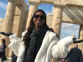 Portrait of woman in sunglasses and warm clothing standing outdoors