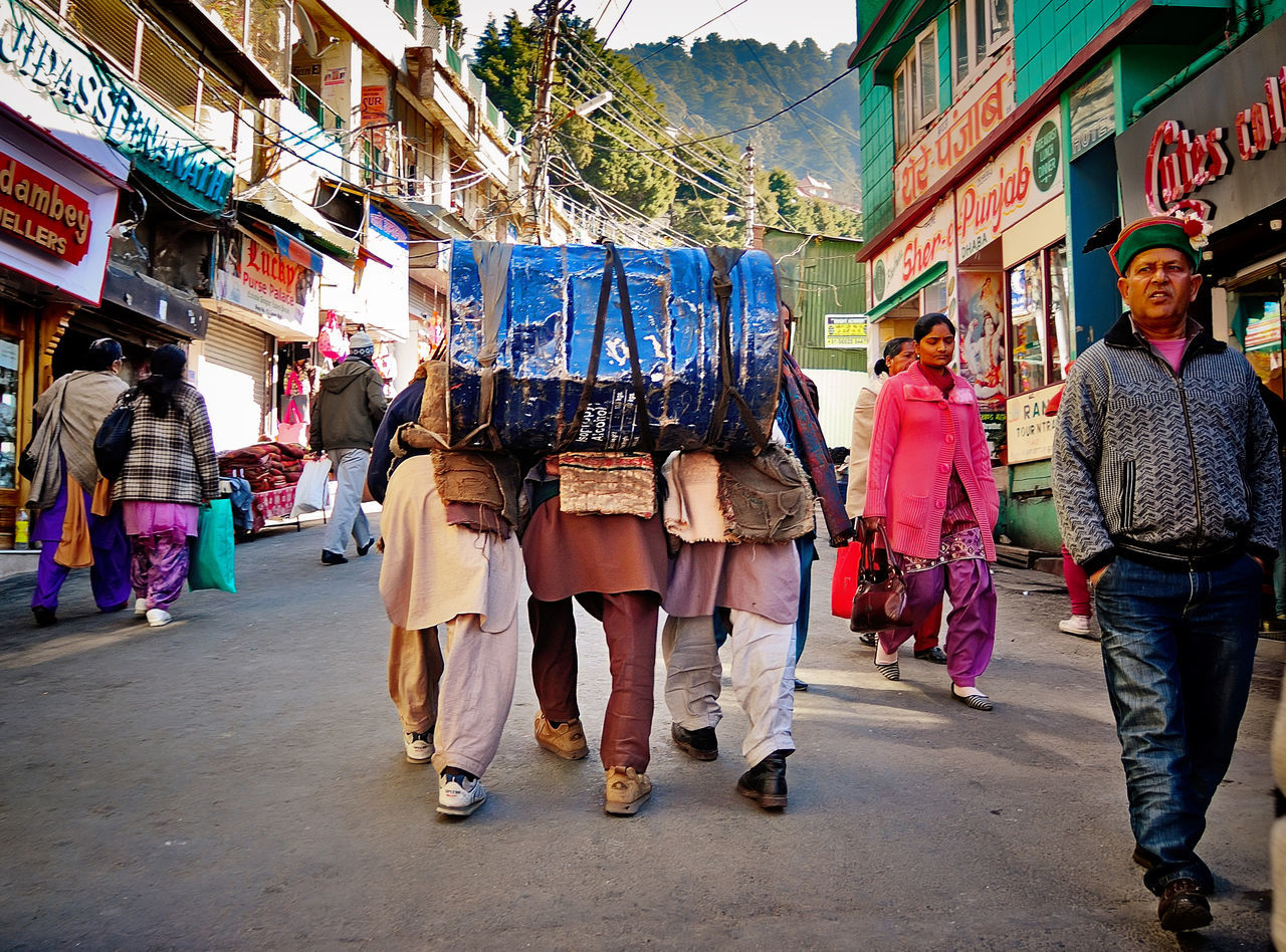 building exterior, men, architecture, built structure, person, street, lifestyles, walking, large group of people, city, leisure activity, casual clothing, city life, full length, rear view, market, day, outdoors, market stall