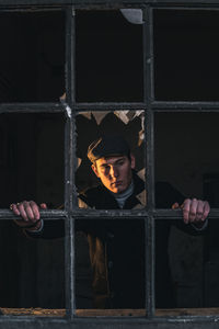 Young man looking through prison bar