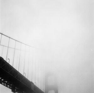 Suspension bridge against cloudy sky