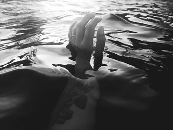 Woman hand emerging from lake water on sunny day