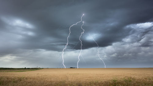 Lightning over field against sky