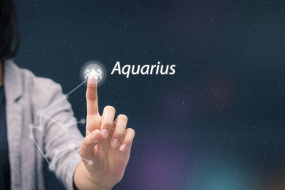 Midsection of woman touching astrology sign on digital display
