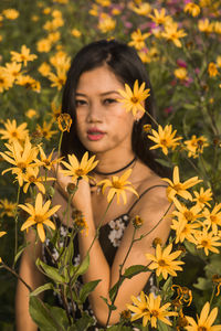 Portrait of woman by yellow blooming flowers