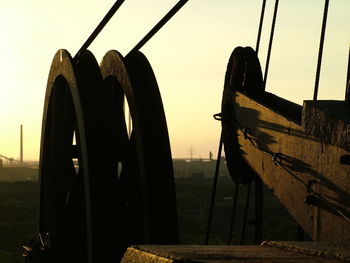 Close-up of silhouette wheel on field against clear sky