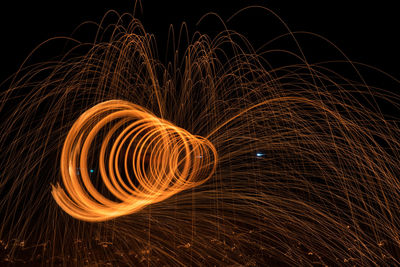 Illuminated wire wool spinning against sky at night