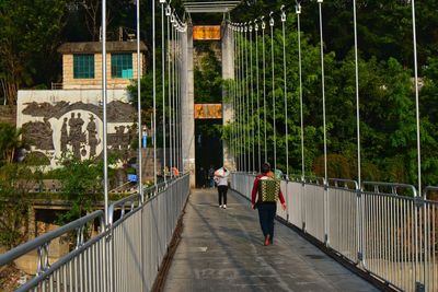 Rear view of people walking on footbridge in city