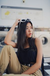 Thoughtful young woman sitting at laundromat