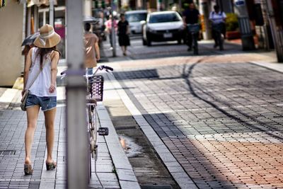 Full length rear view of woman walking on sidewalk in city