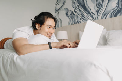 Young woman using laptop on bed at home