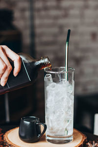 Close-up of hand pouring coffee in glass