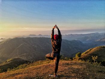 Rear view of man doing yoga pose on mountain