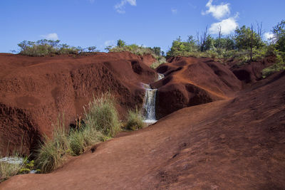 A small waterfall with a bright blue sky in the background. photographed in waimea canyon state park