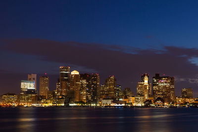 Illuminated modern buildings in city against sky at night