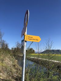 Road sign on field against clear sky