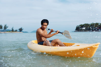 Shirtless man swimming in sea