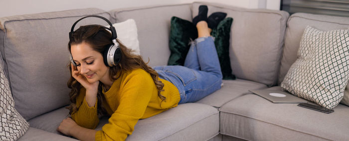 Rear view of woman sitting on sofa at home