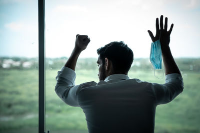Rear view of man drinking water from glass window