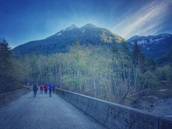 Rear view of people walking on road against mountain range